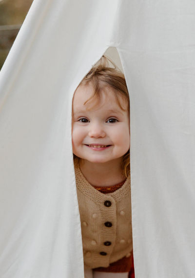 A little girl looking out of a tent